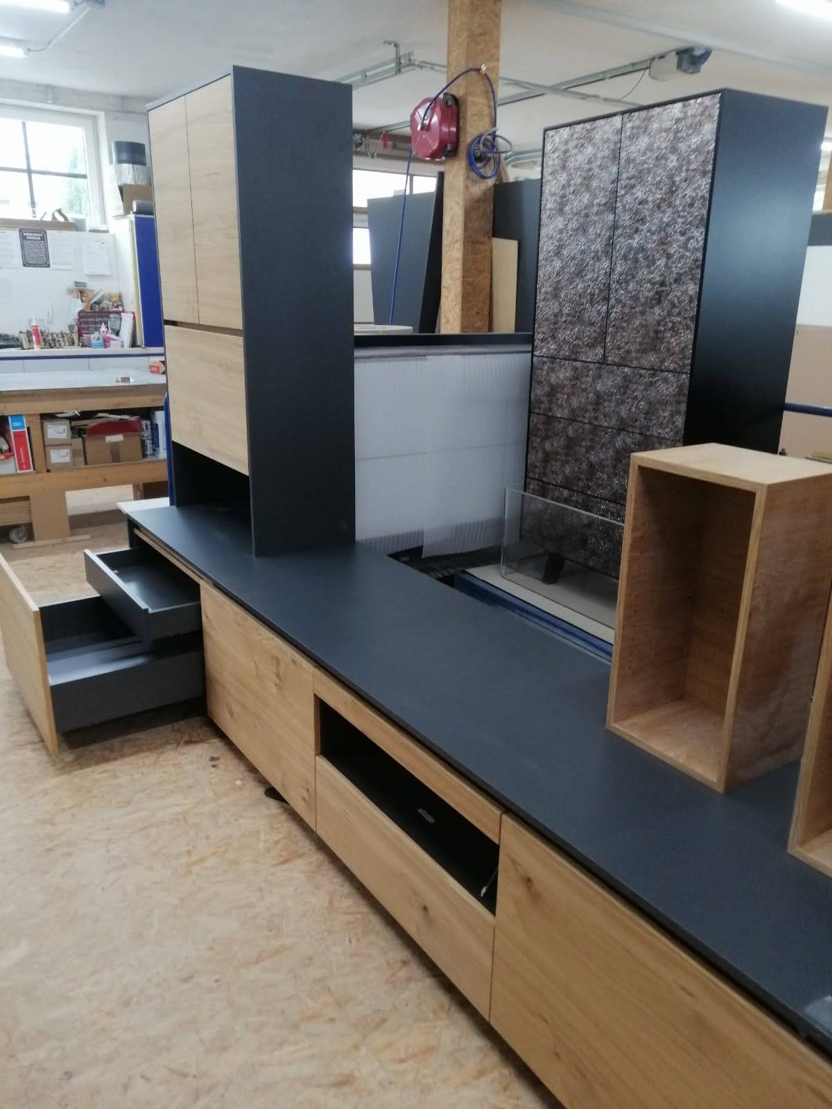 Modul-Schrankwand mit Steinstruktur-Paneelen und ausgezogener Schublade in der Werkstatt